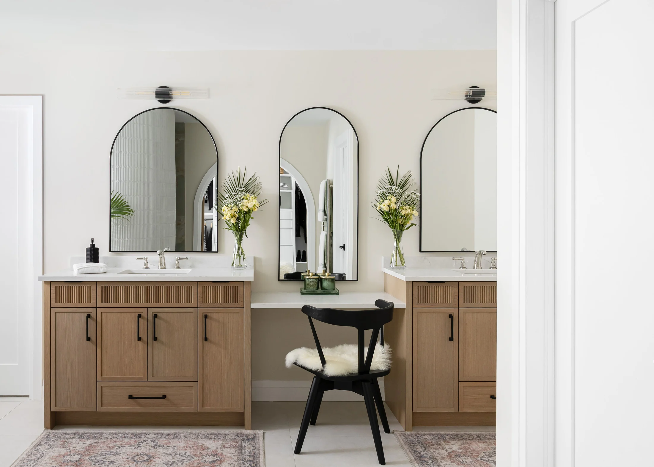 Warm oak bathroom cabinetry with arched mirrors and brass fixtures