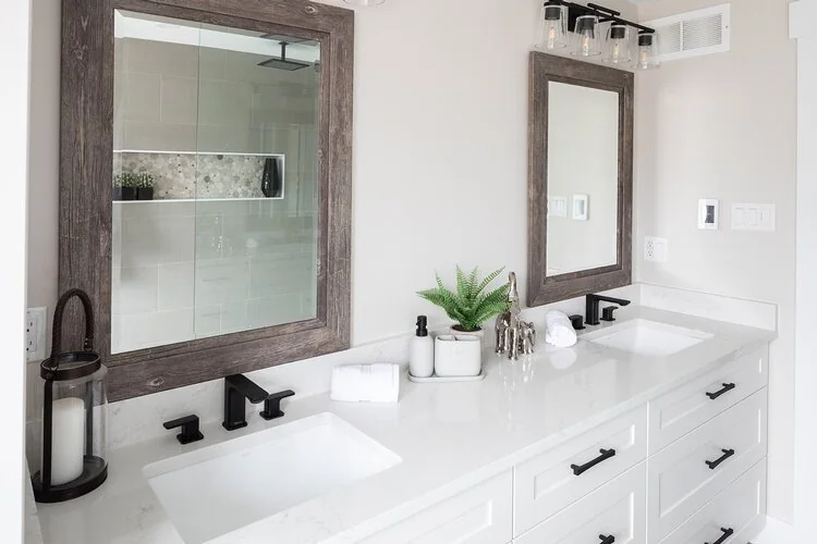 Bathroom double vanity with white drawers, dark fittings and framed mirrors at Caldwell II