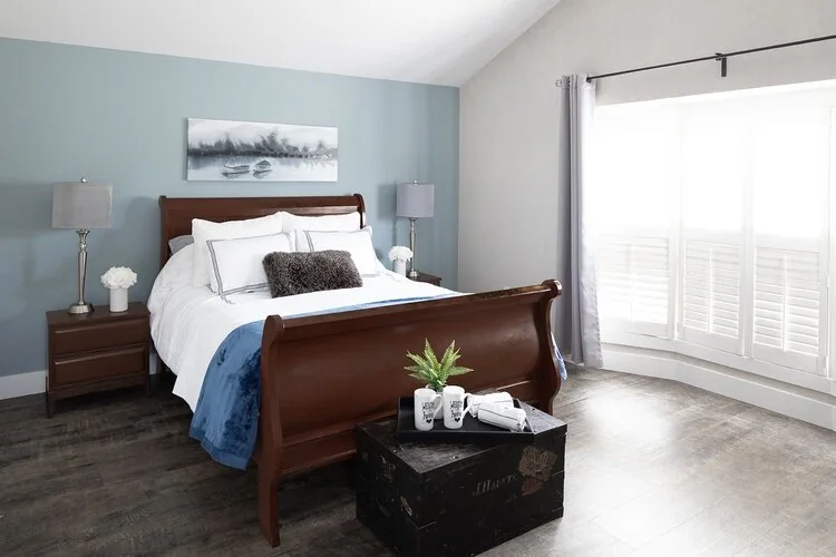Bedroom with a wood bed, pale blue walls and a large window at Caldwell II