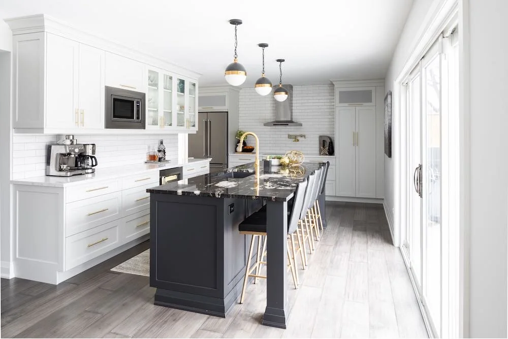 Kitchen with white cabinets, a dark island and three pendant lights at Devlin I