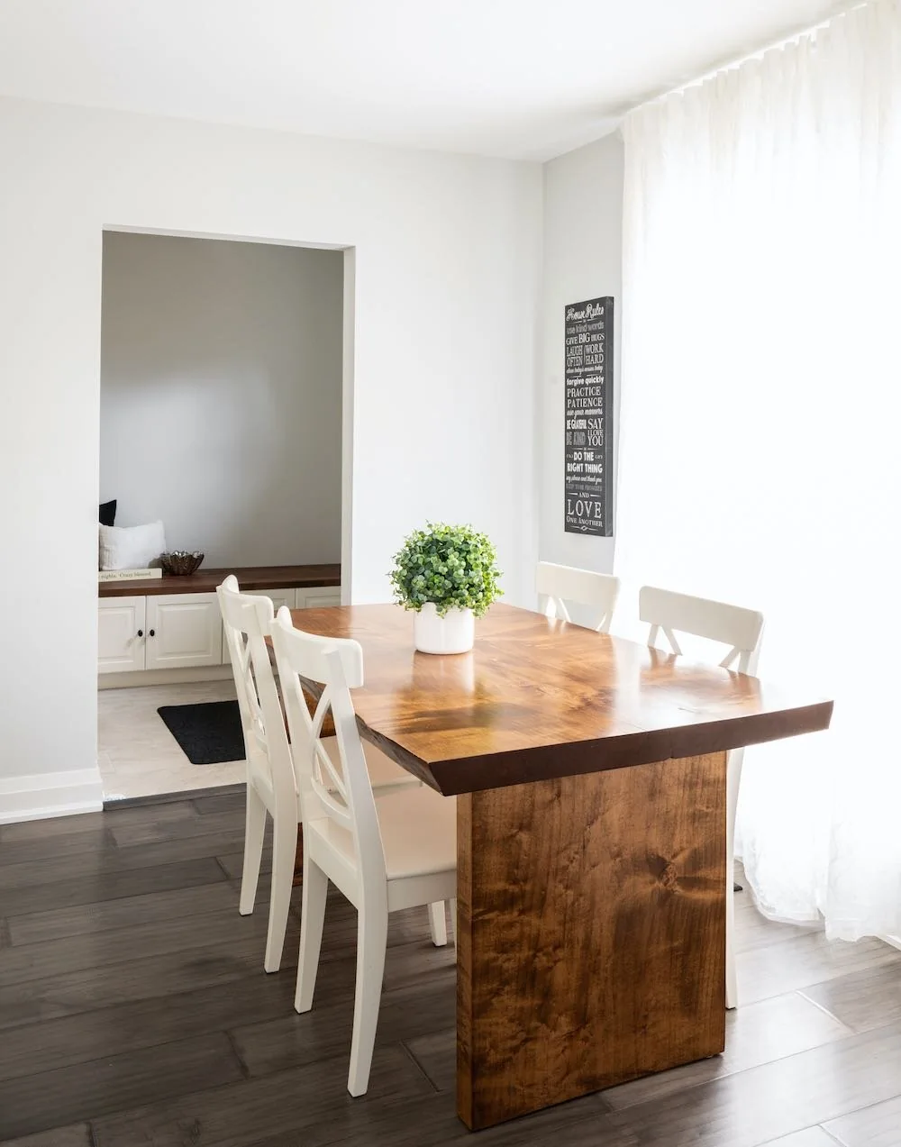 Dining area with a wood table and white chairs beside a window at Devlin I
