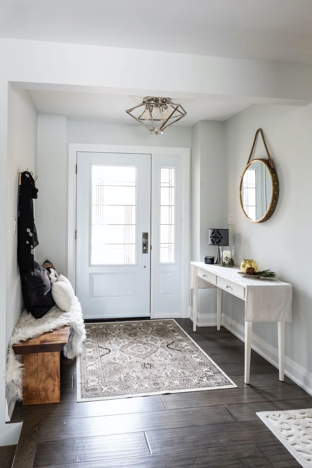 Front entry with a pale door, round mirror and narrow console at Devlin I