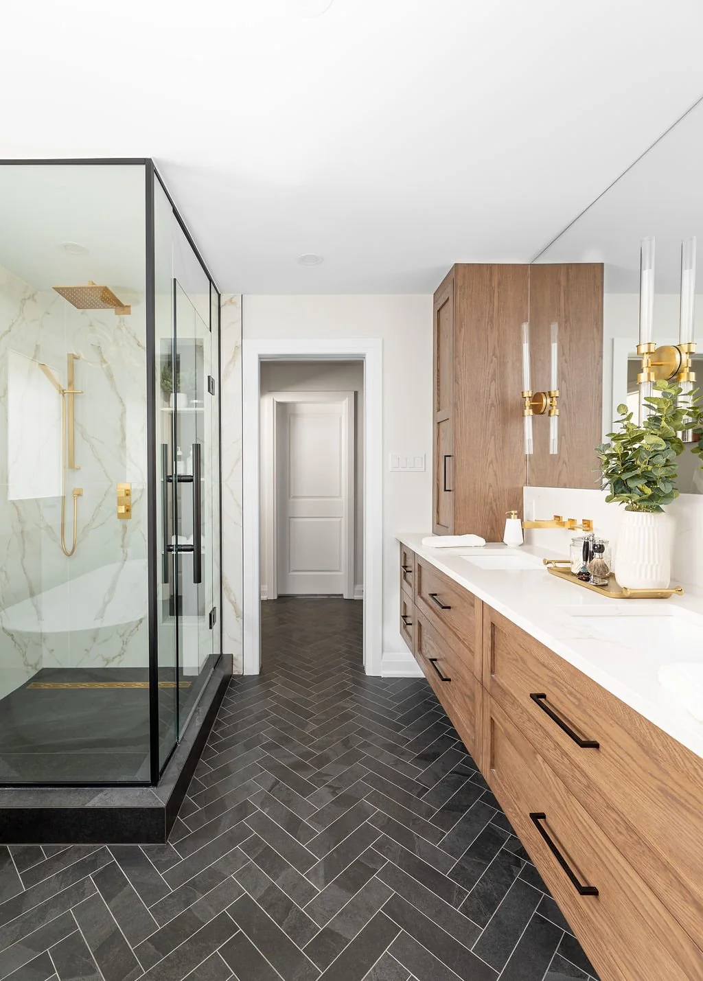 Bathroom with a long wood vanity, glass shower and dark herringbone floor at Devlin II