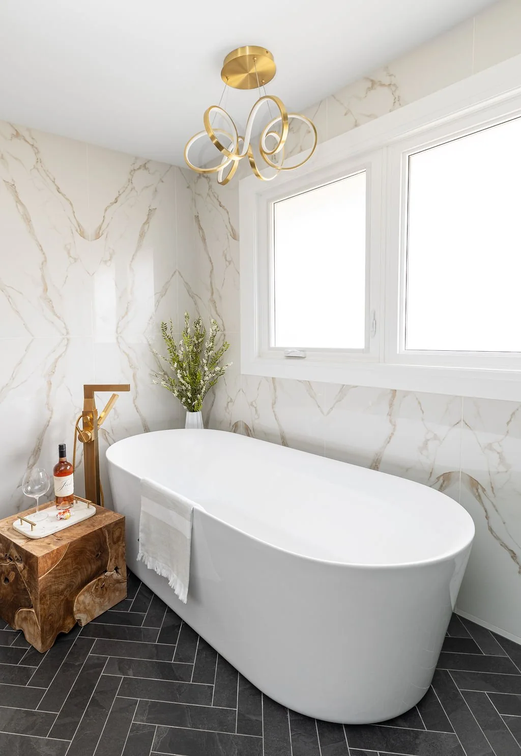 Freestanding white tub below a window with brass-coloured fittings at Devlin II