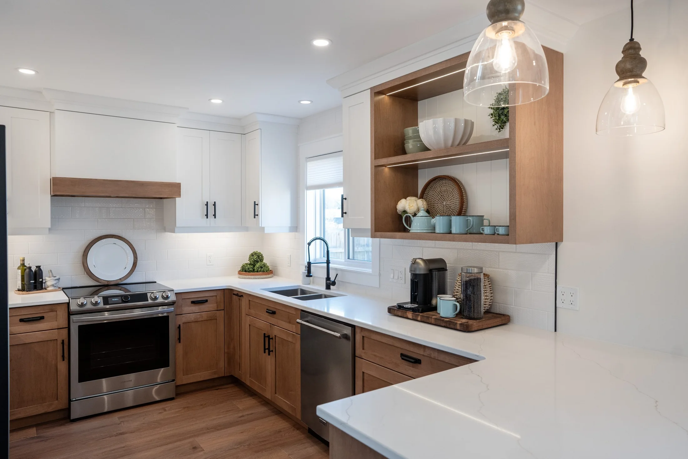 Kitchen with wood base cabinets, white upper cabinets and glass pendant lights at Joseph I