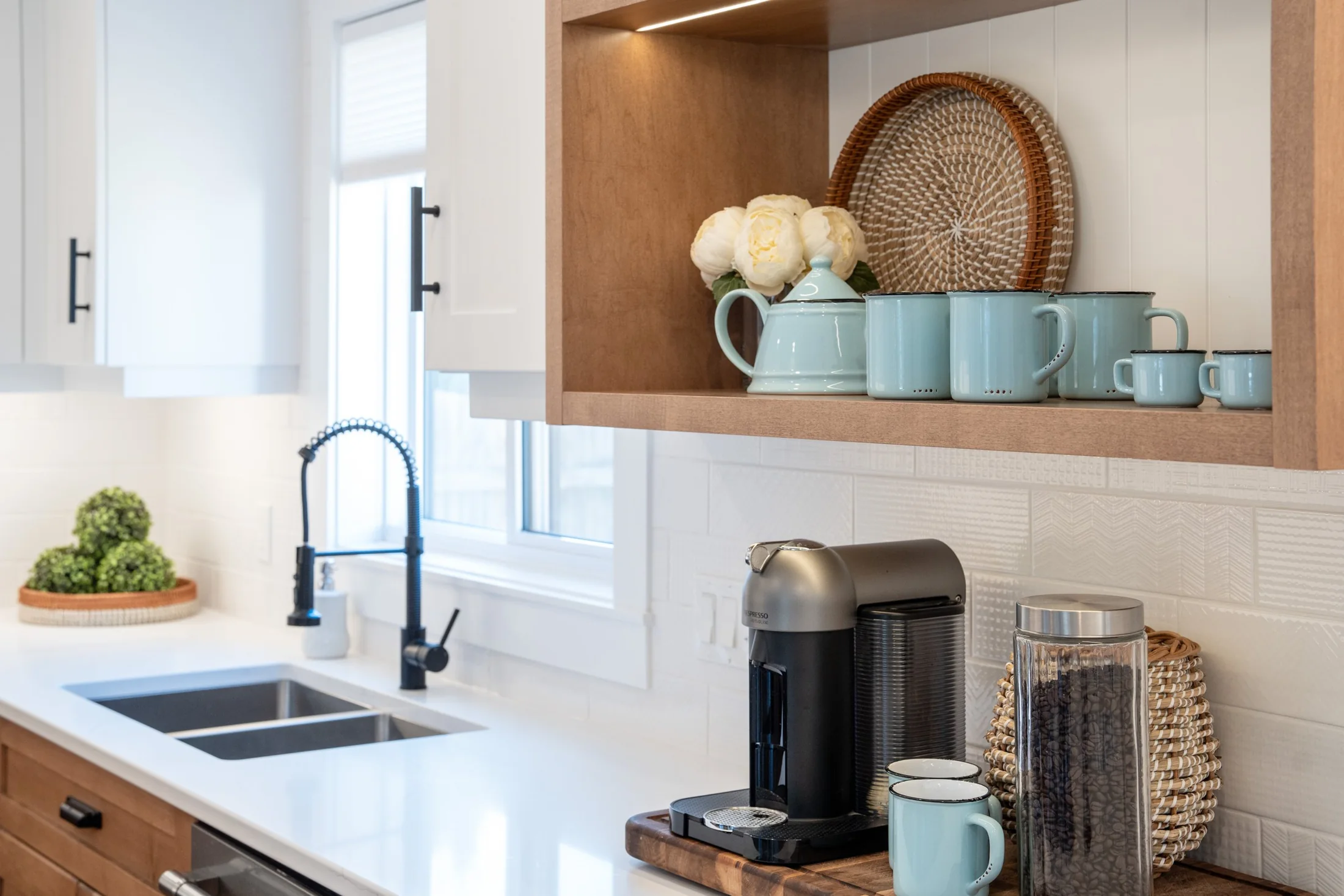 Kitchen sink and wood display shelving above a white counter at Joseph I
