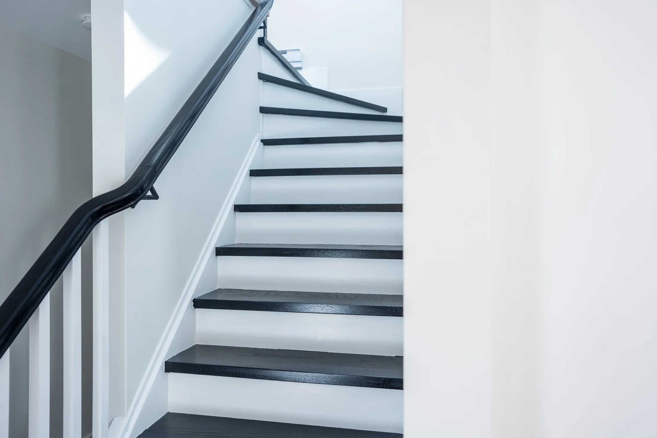 Staircase with dark treads, white risers and a dark handrail at Joseph I
