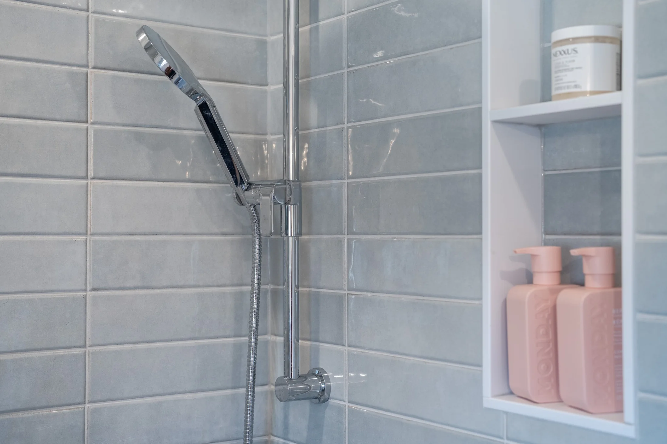 Grey tiled shower with a handheld showerhead and recessed storage at Joseph I