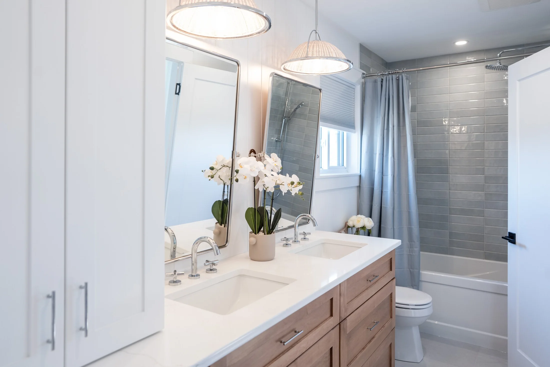 Bathroom with wood vanity drawers, tall white cabinets and a tiled shower at Joseph I