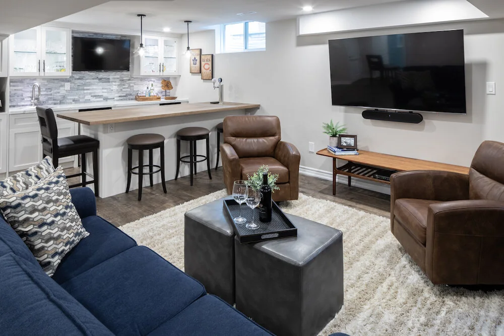 Basement living room with a blue sofa, leather armchairs and a bar at Kingsridge I
