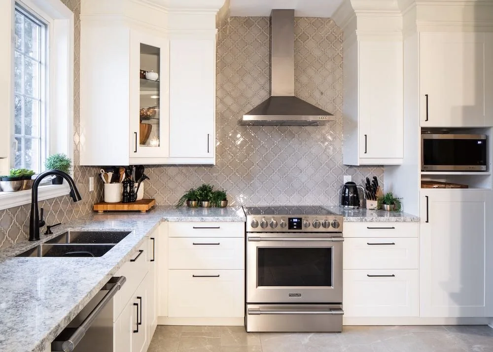 White kitchen with a patterned backsplash and stainless steel range hood at Mariposa I