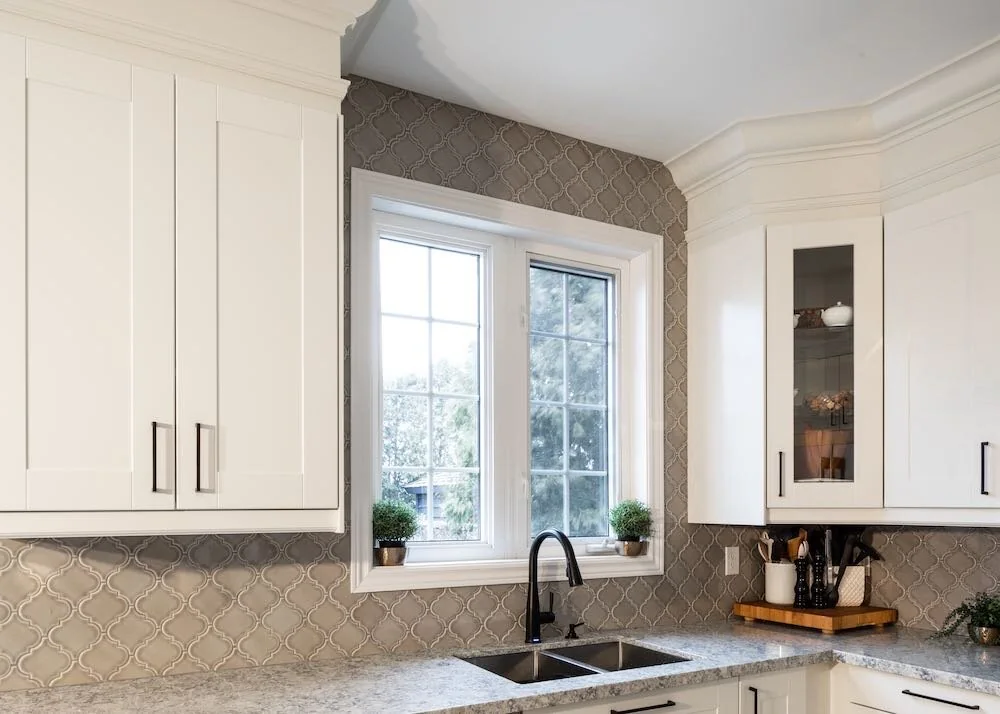 Kitchen sink beneath a window with white cabinets on either side at Mariposa I