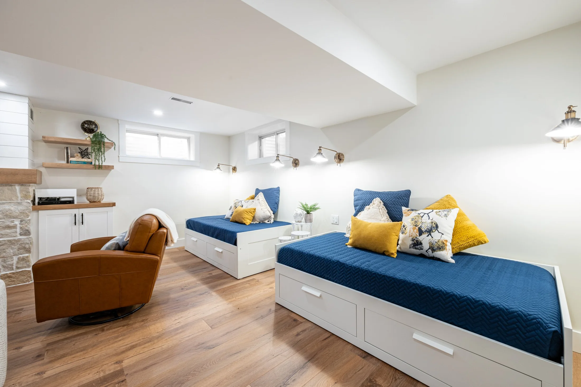 Basement daybeds with blue cushions and white storage drawers at Mill Creek I
