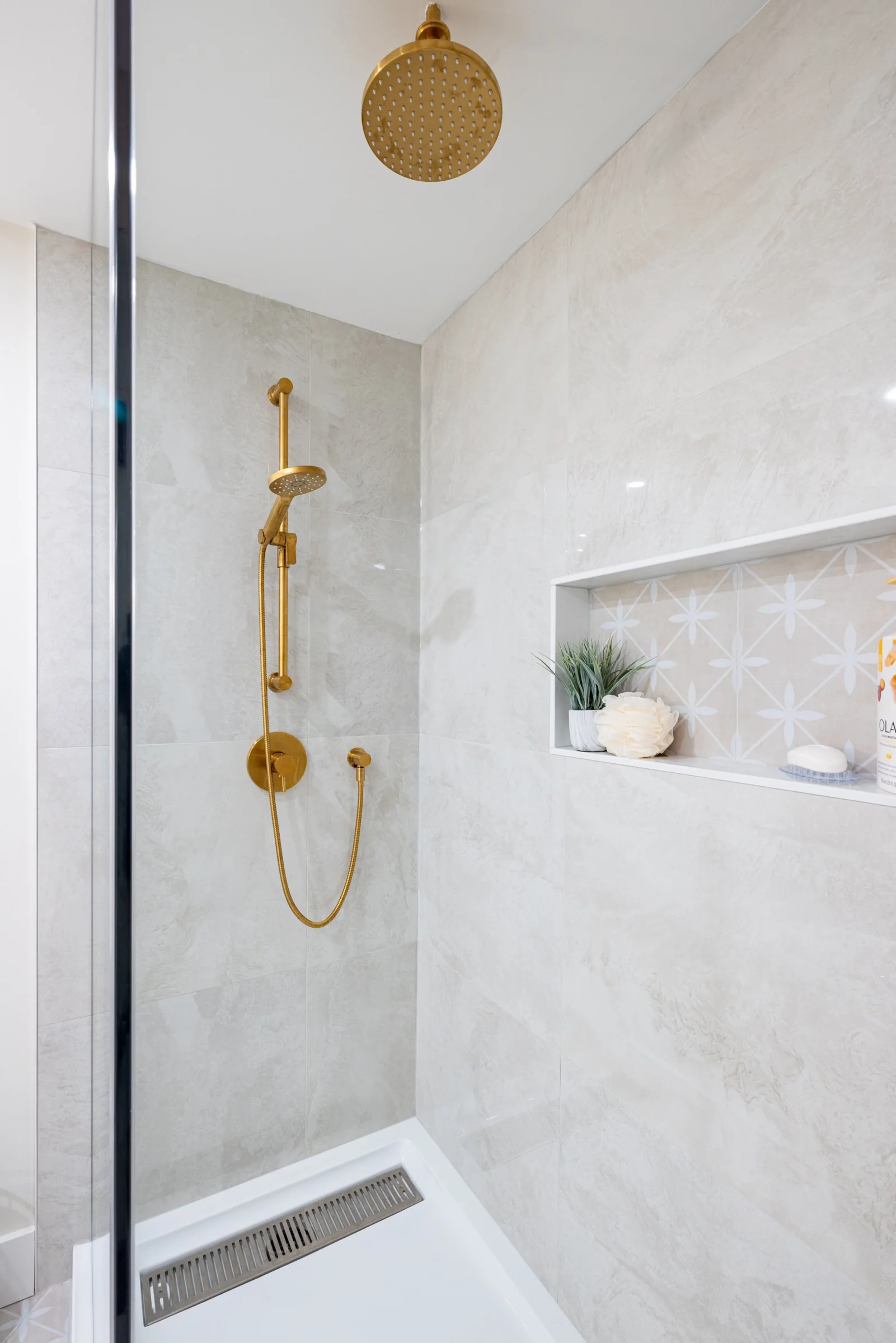 Tiled shower with a recessed shelf and brass-coloured fixtures at Mill Creek I
