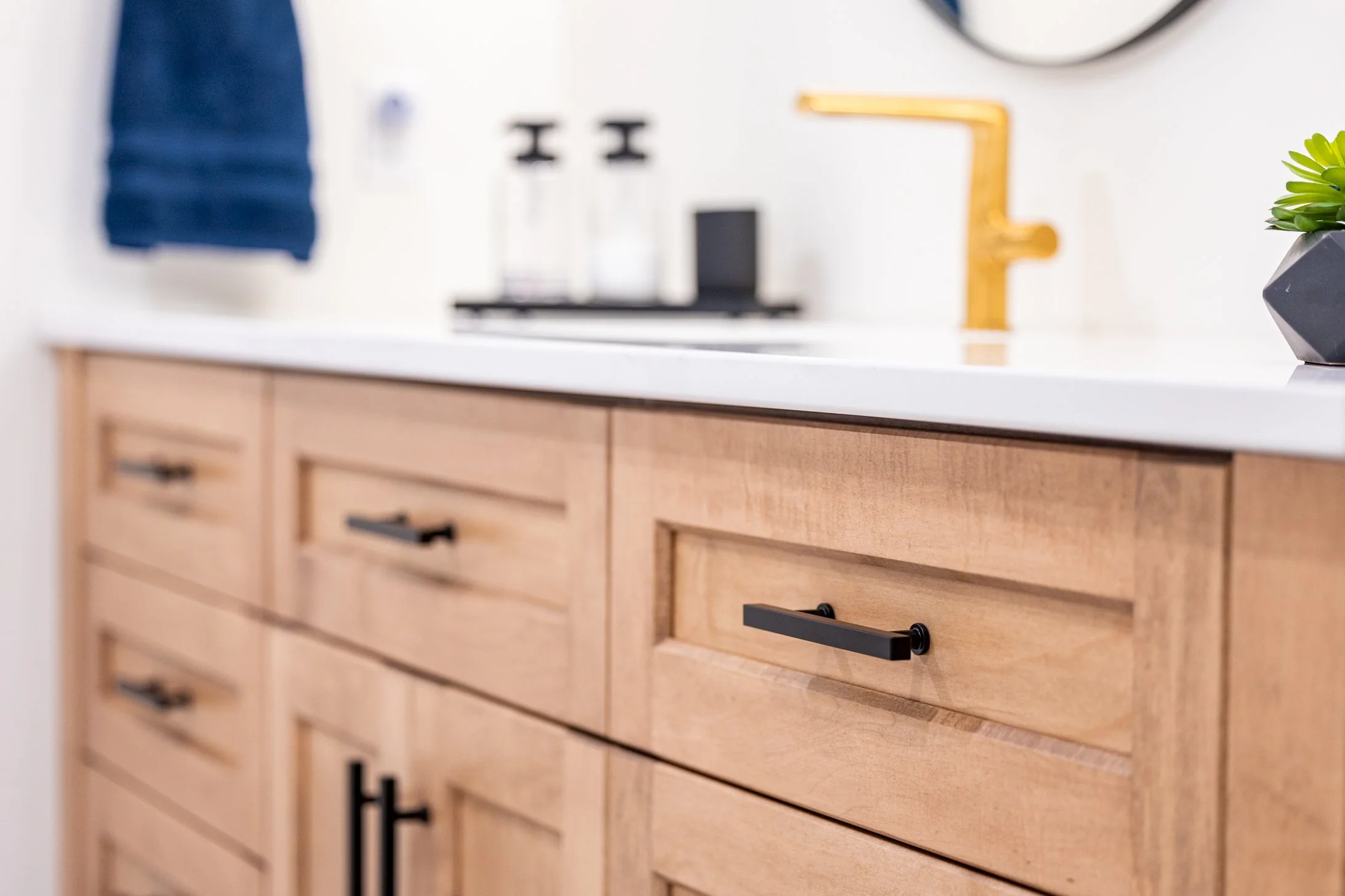 Wood vanity drawers with dark pulls and a white counter at Mill Creek I