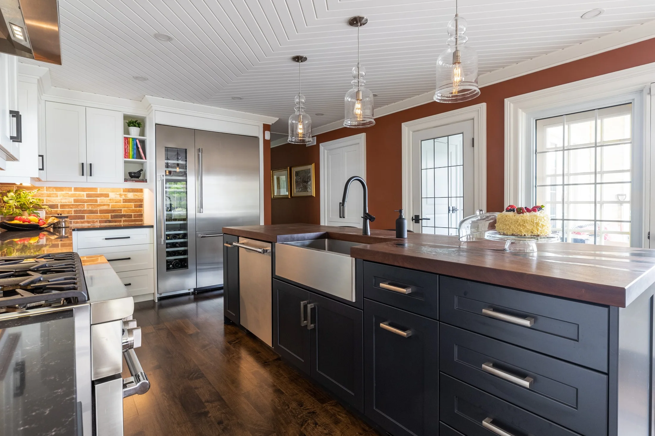 Kitchen with a dark island, wood counter, white cabinets and orange walls at South Rankin I