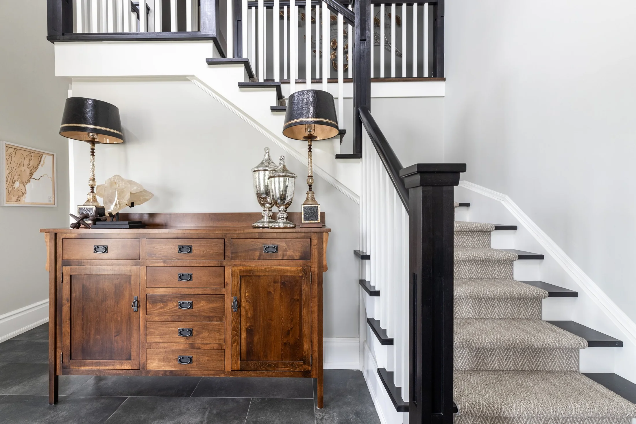 Entry with a wood cabinet and staircase with dark rails and white balusters at South Rankin I