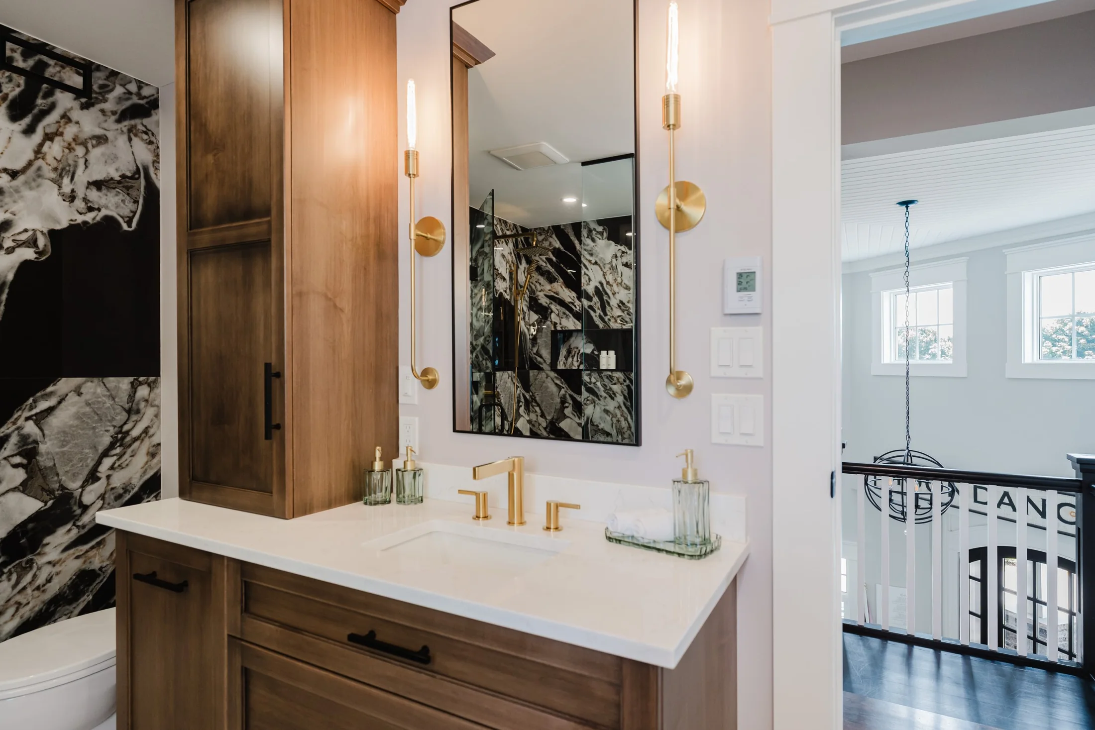 Wood bathroom vanity with a tall mirror and brass-coloured fittings at South Rankin II